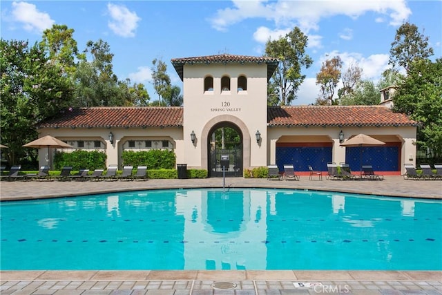 back of house with a community pool and a patio