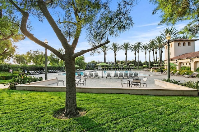 view of home's community with a pool and a lawn