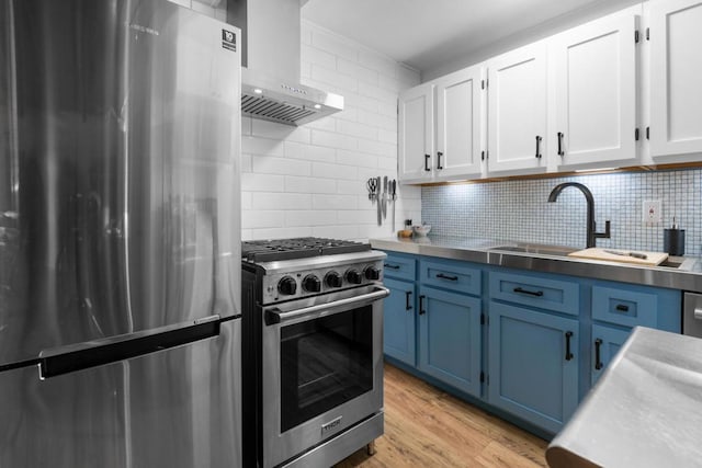 kitchen with appliances with stainless steel finishes, blue cabinets, extractor fan, and white cabinets