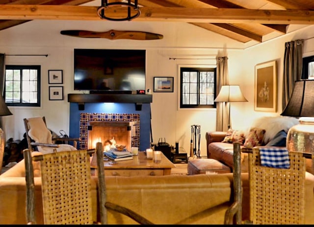 living room with lofted ceiling with beams and a tiled fireplace