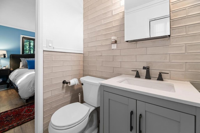 bathroom with tile walls, vanity, ornamental molding, and toilet