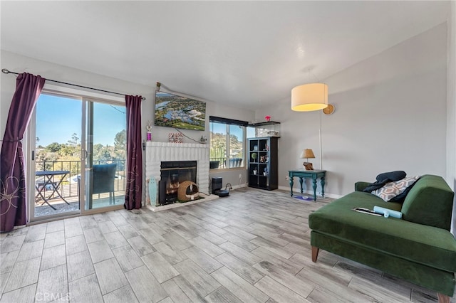 living room featuring a healthy amount of sunlight, a brick fireplace, baseboards, and wood finished floors