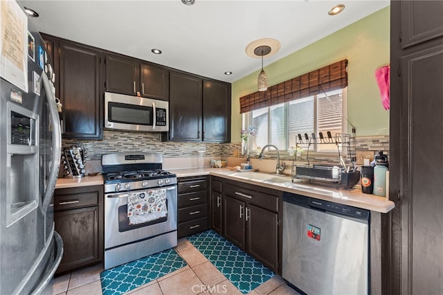 kitchen featuring light countertops, appliances with stainless steel finishes, a sink, and tasteful backsplash