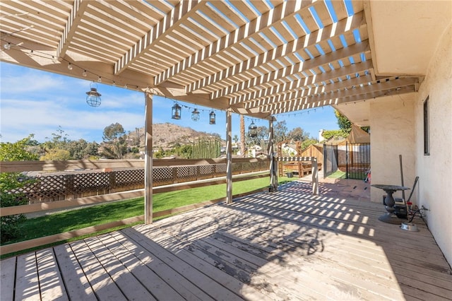 deck featuring a fenced backyard, a lawn, and a pergola