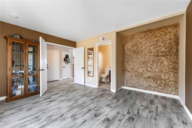 spare room with baseboards, visible vents, and wood finished floors