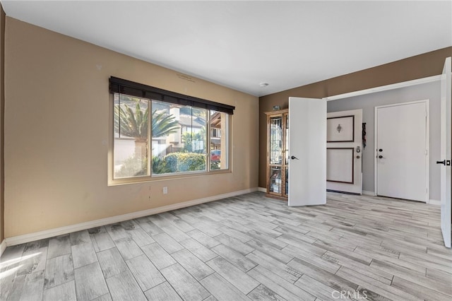 empty room with light wood-type flooring and baseboards