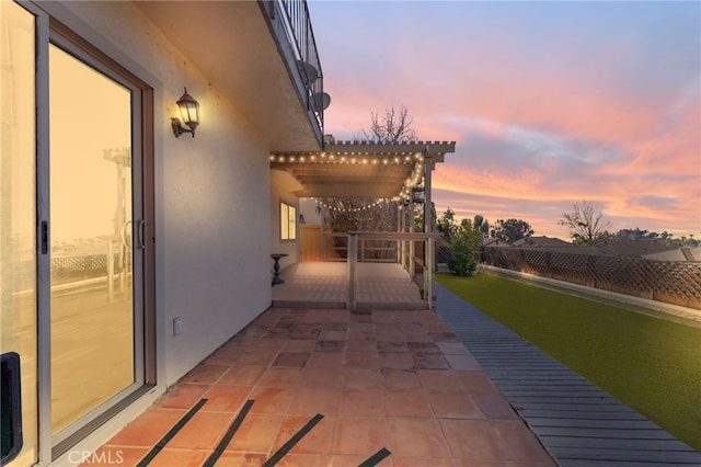 patio terrace at dusk featuring fence