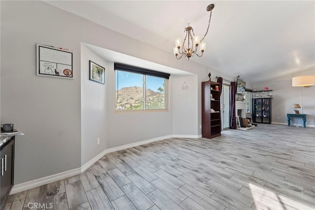 unfurnished dining area with a chandelier, wood finish floors, and baseboards