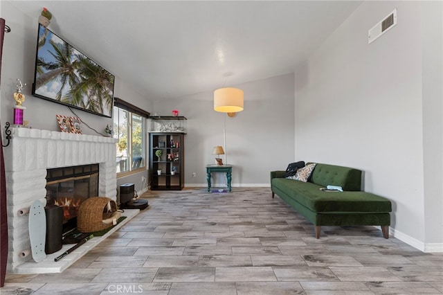 sitting room featuring vaulted ceiling, a brick fireplace, visible vents, and baseboards