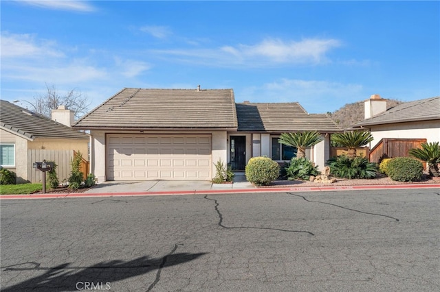 view of front of home with a garage, concrete driveway, fence, and a tiled roof