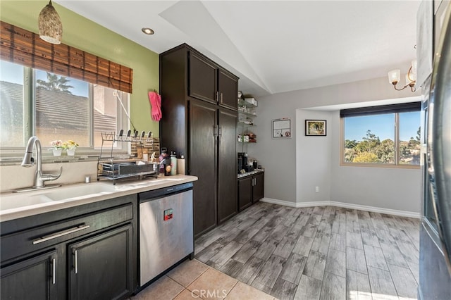 kitchen with stainless steel appliances, light countertops, vaulted ceiling, a sink, and baseboards