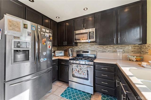 kitchen featuring light tile patterned floors, stainless steel appliances, backsplash, and light countertops