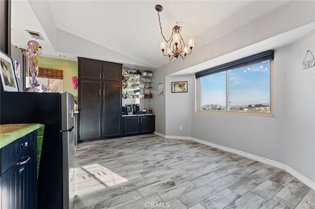 unfurnished dining area with a notable chandelier, visible vents, vaulted ceiling, light wood-type flooring, and baseboards