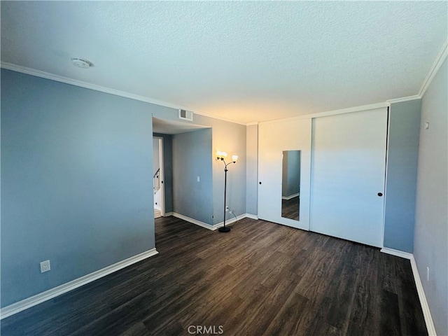 unfurnished bedroom featuring crown molding, visible vents, a textured ceiling, wood finished floors, and baseboards