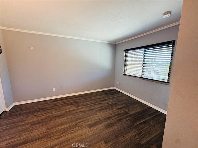 spare room with dark wood-style floors, crown molding, and baseboards