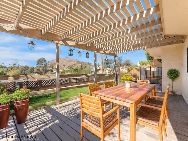 wooden deck featuring outdoor dining space, a fenced backyard, and a yard