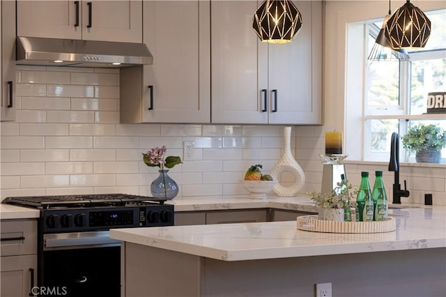 kitchen featuring pendant lighting, range with gas stovetop, light stone counters, and exhaust hood