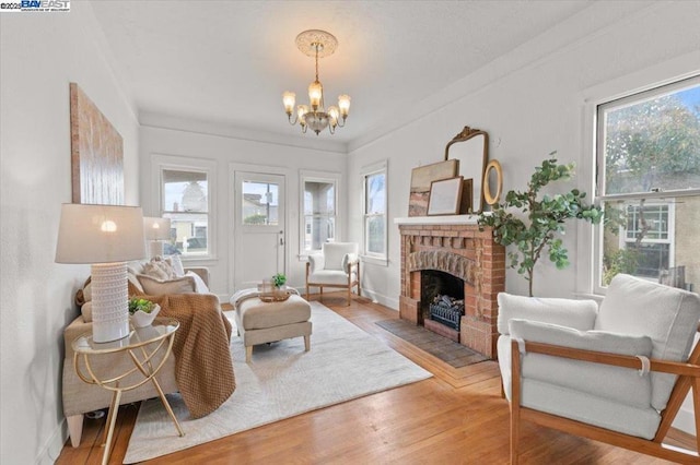 sitting room featuring wood-type flooring, a brick fireplace, and a notable chandelier