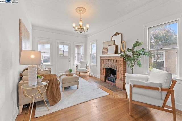 sitting room featuring a brick fireplace, wood-type flooring, and a chandelier