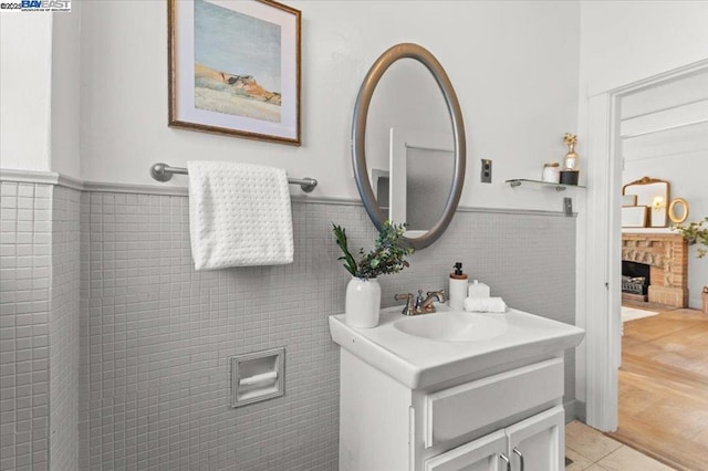 bathroom featuring vanity, tile patterned flooring, a fireplace, and tile walls