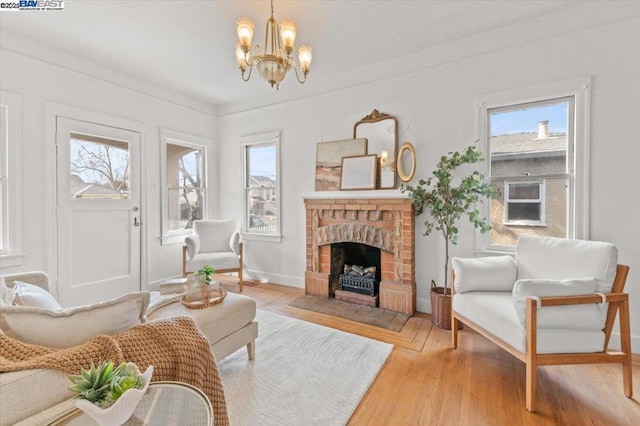 living area featuring plenty of natural light, hardwood / wood-style floors, an inviting chandelier, and a brick fireplace