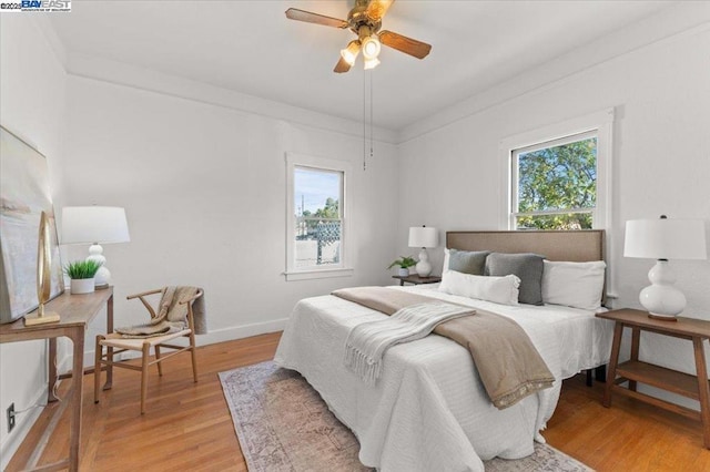 bedroom with multiple windows, crown molding, ceiling fan, and light hardwood / wood-style flooring