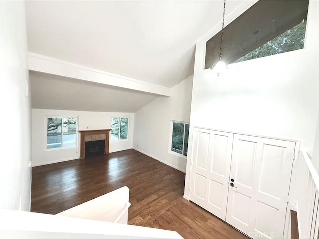 unfurnished living room with dark wood-type flooring, baseboards, vaulted ceiling, and a tiled fireplace