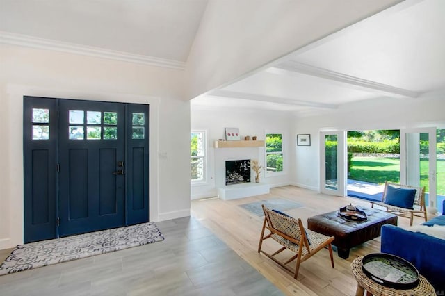 foyer entrance with lofted ceiling with beams, ornamental molding, and light wood-type flooring