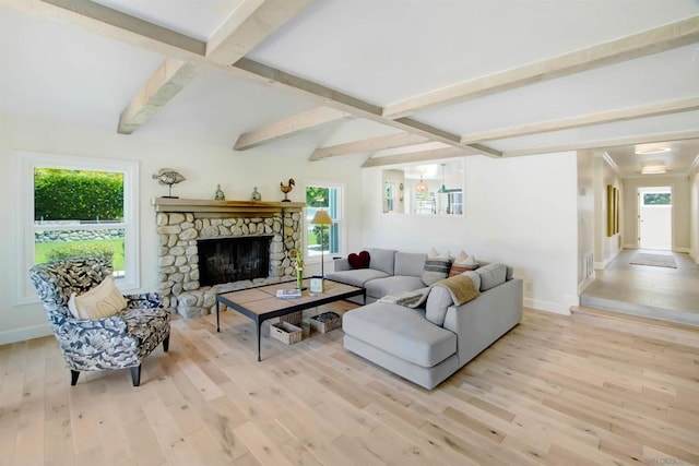 living room with beam ceiling, a stone fireplace, and light wood-type flooring