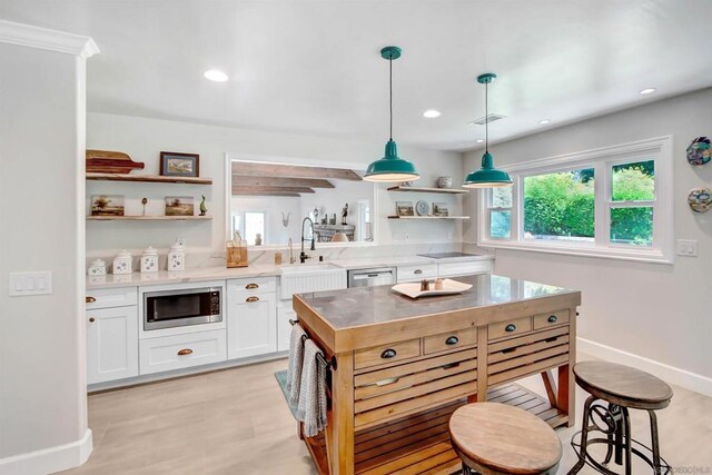 kitchen featuring a breakfast bar, sink, white cabinetry, hanging light fixtures, and appliances with stainless steel finishes