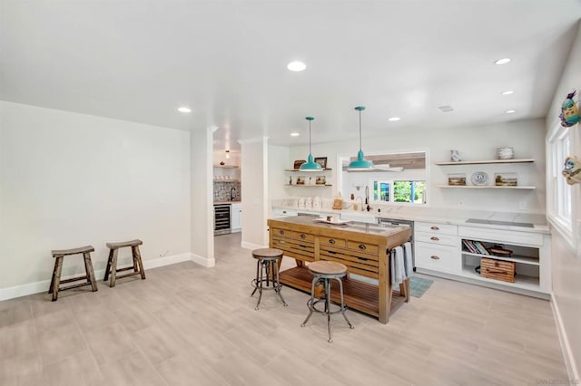 kitchen featuring wine cooler, white cabinetry, hanging light fixtures, a kitchen breakfast bar, and black electric stovetop