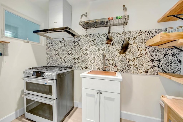 kitchen featuring tasteful backsplash, double oven range, range hood, and white cabinets