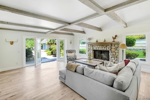 living room with a stone fireplace, light hardwood / wood-style flooring, and beamed ceiling