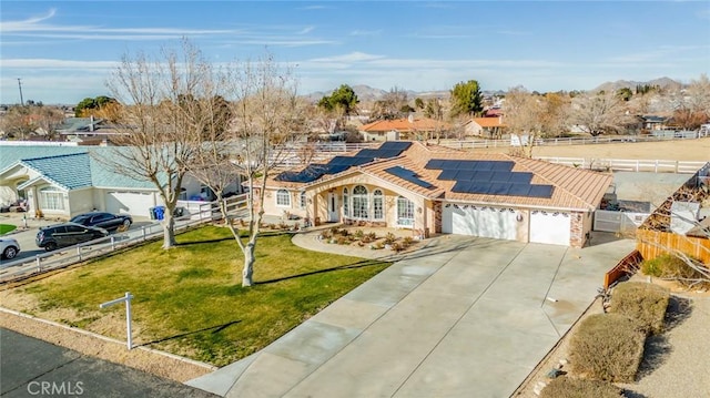 ranch-style home with a garage, a front lawn, and solar panels