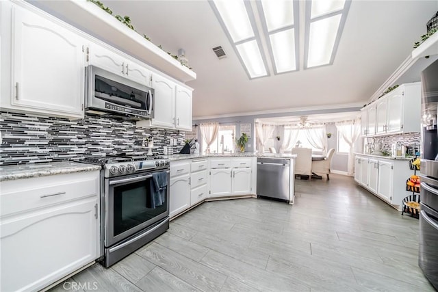 kitchen with white cabinetry, appliances with stainless steel finishes, light wood-type flooring, and backsplash