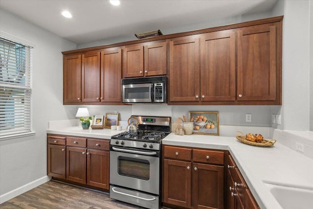 kitchen with appliances with stainless steel finishes, dark hardwood / wood-style floors, and sink