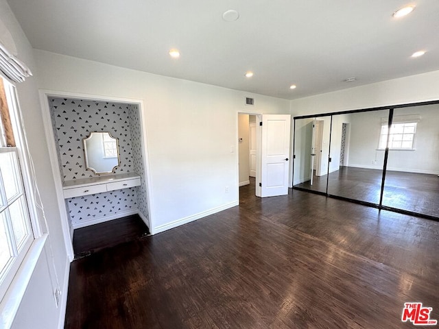 unfurnished bedroom with connected bathroom, dark hardwood / wood-style floors, and a closet