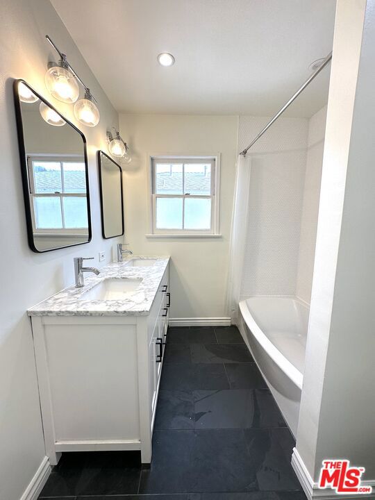 bathroom with vanity, plenty of natural light, and shower / tub combo with curtain