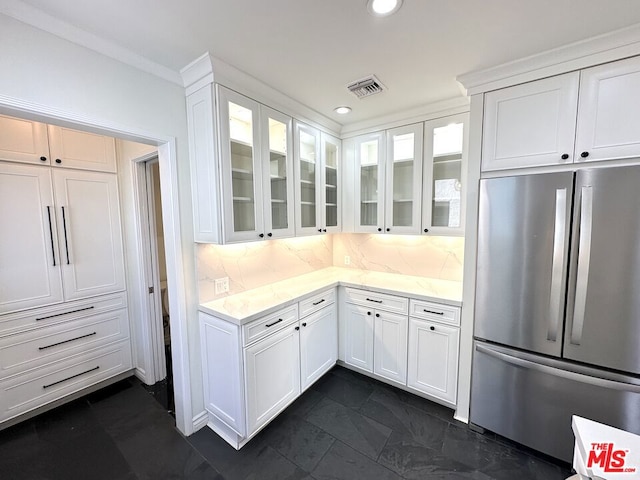 kitchen featuring white cabinetry, backsplash, and stainless steel refrigerator