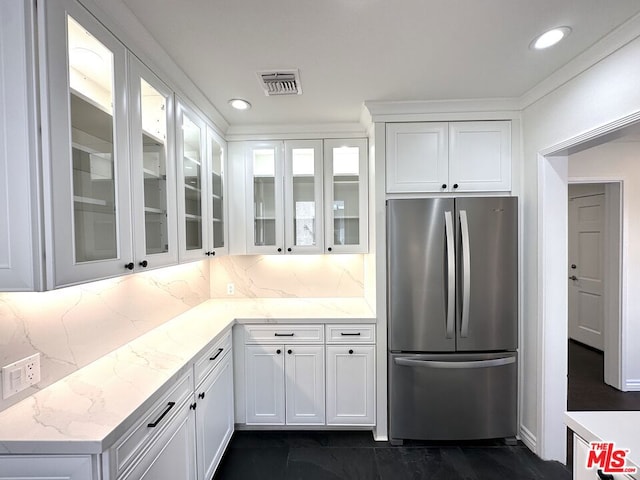 kitchen with backsplash, stainless steel fridge, light stone countertops, and white cabinets