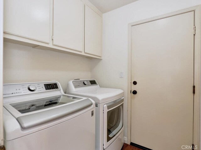 clothes washing area with washing machine and dryer and cabinets