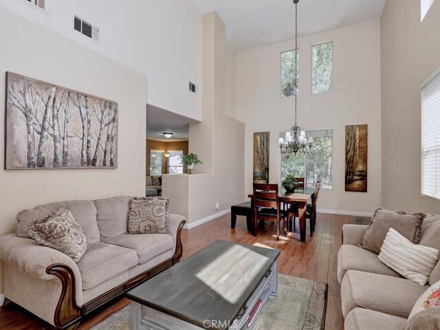 living room featuring a notable chandelier, hardwood / wood-style flooring, and a high ceiling