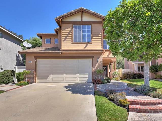 traditional-style house featuring driveway, an attached garage, a tile roof, and stucco siding