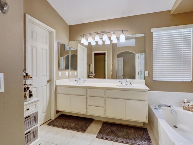 bathroom with tile patterned flooring, vanity, and a bath