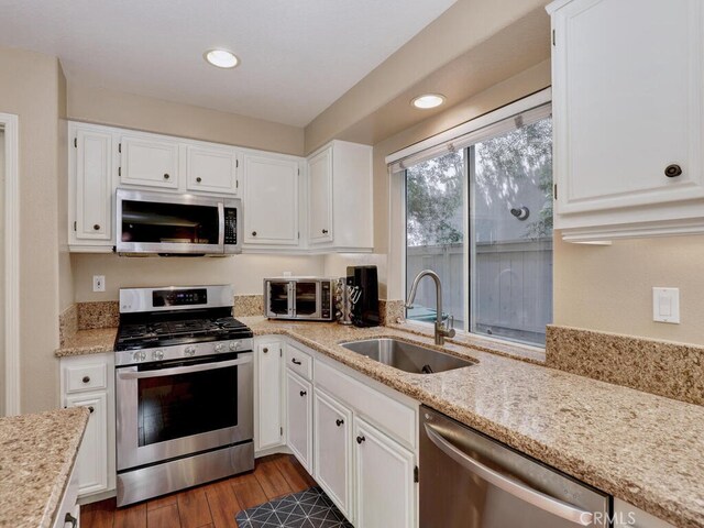 kitchen featuring appliances with stainless steel finishes, sink, white cabinets, and dark hardwood / wood-style flooring