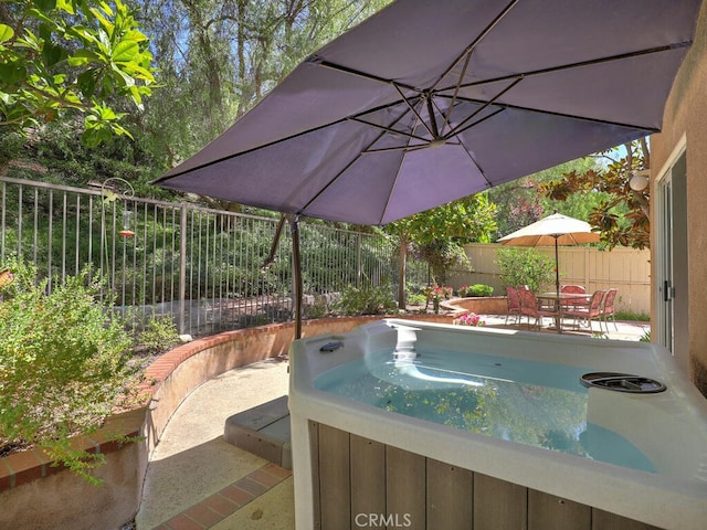 view of pool with a hot tub, outdoor dining area, and a fenced backyard