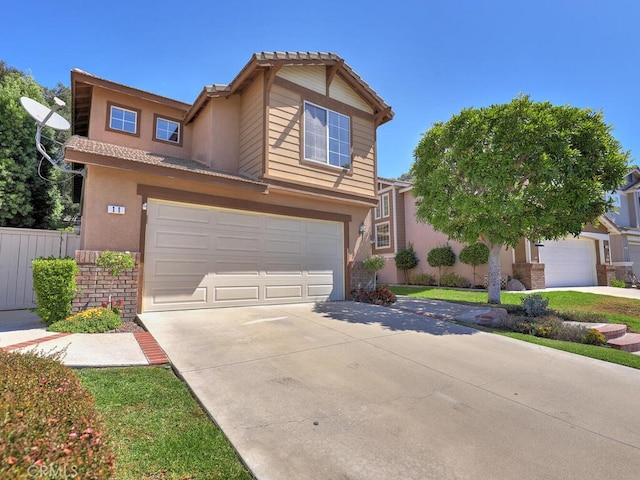 view of front facade with driveway, fence, an attached garage, and stucco siding