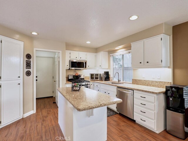 kitchen with appliances with stainless steel finishes, a center island, sink, and white cabinets