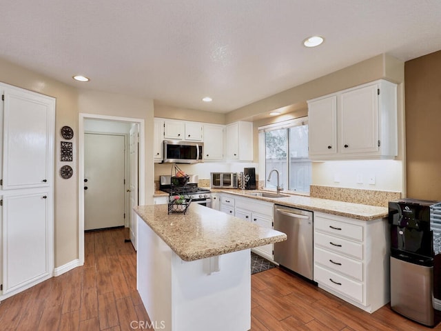 kitchen featuring white cabinetry, appliances with stainless steel finishes, a sink, and wood finished floors