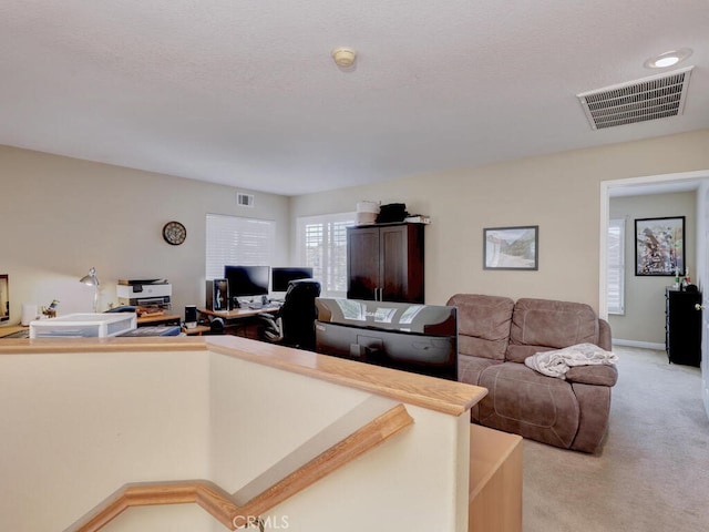 living area with visible vents, a textured ceiling, and light colored carpet